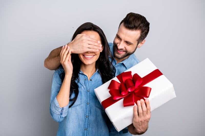 man hand holding gift and one hand woman eye