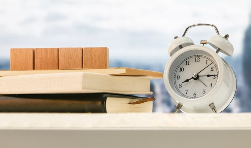 alarm-clock-cubes-and-books-on-wooden-table